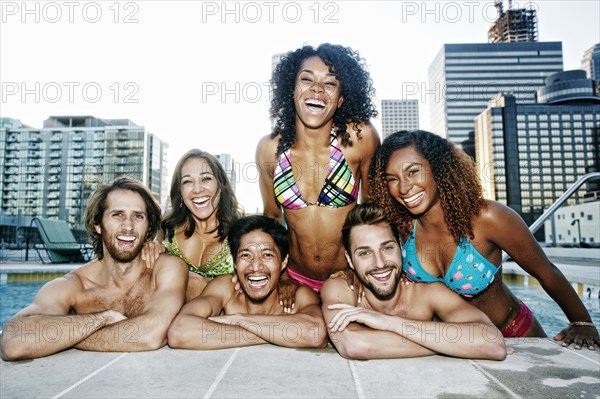 Smiling friends relaxing poolside at urban swimming pool