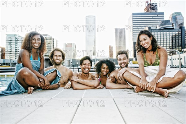 Smiling friends relaxing poolside at urban swimming pool