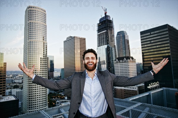 Caucasian businessman celebrating on urban rooftop