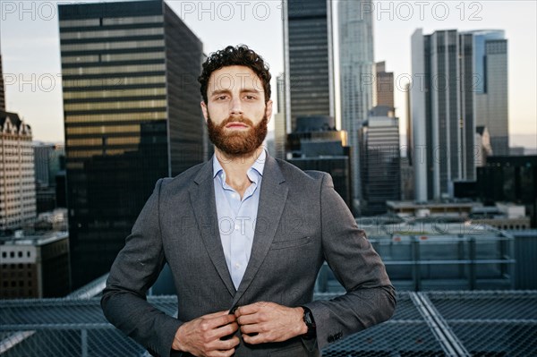 Caucasian businessman buttoning jacket on urban rooftop