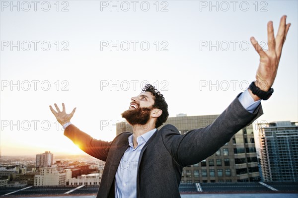Caucasian businessman celebrating on urban rooftop