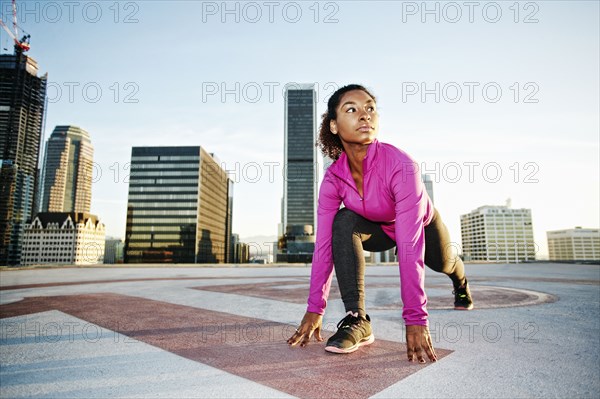 Black woman stretching legs on urban rooftop