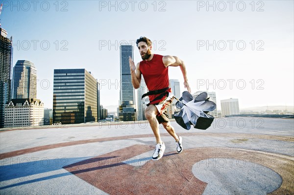 Caucasian man doing resistance training with parachute on rooftop