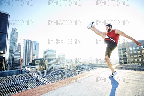Caucasian man kicking on urban rooftop