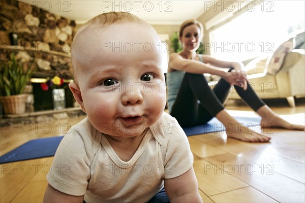 Baby crawling on floor while mother rests from workout