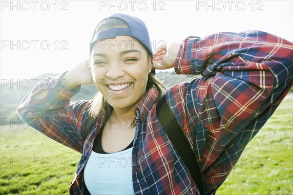 Smiling Mixed Race woman backpacking in field