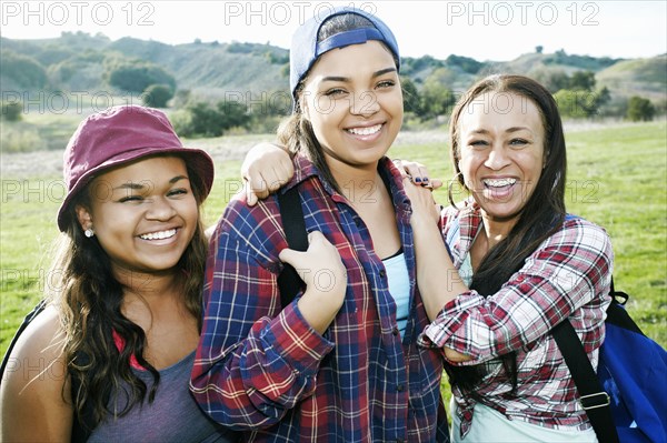 Mixed Race mother and daughters backpacking in field