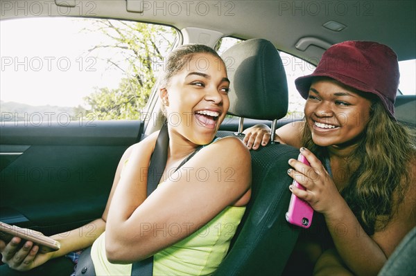 Mixed Race sisters laughing in car