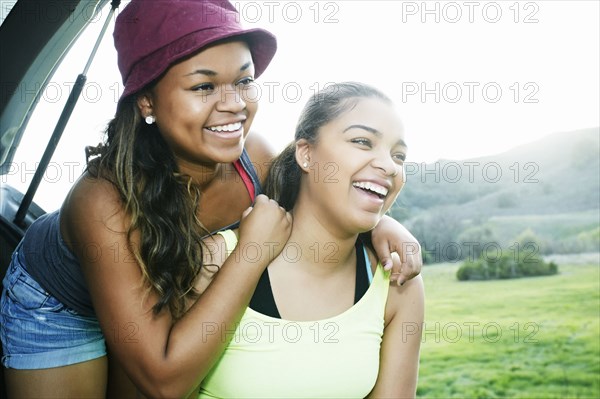 Mixed Race sisters at hatch of car laughing