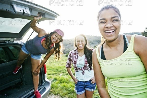 Mixed Race mother and daughters at hatch of car laughing