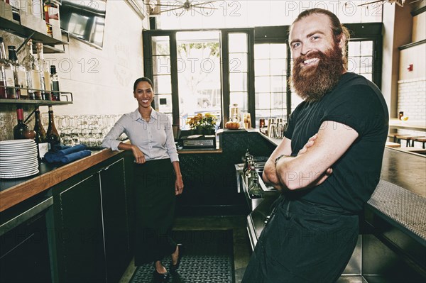 Smiling bartenders relaxing behind bar