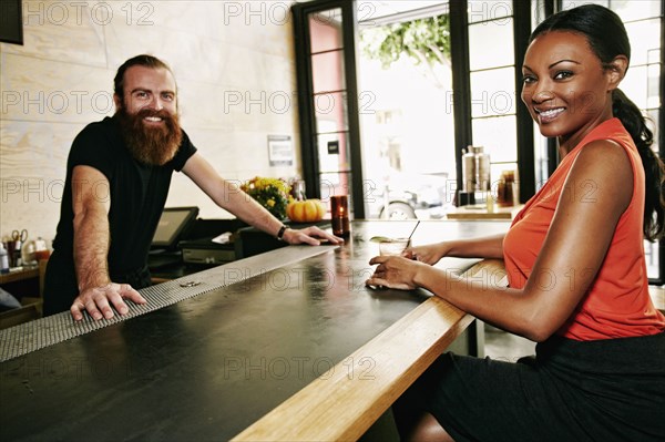 Smiling bartender and customer at bar