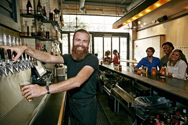 Smiling bartender pouring beer at bar
