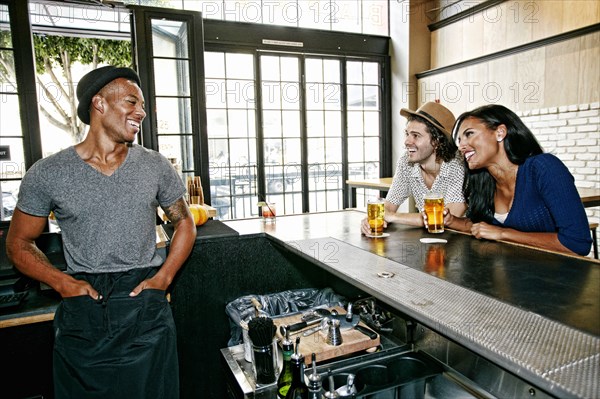 Smiling bartender and customers at bar