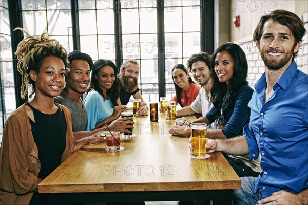 Smiling friends posing at table in bar