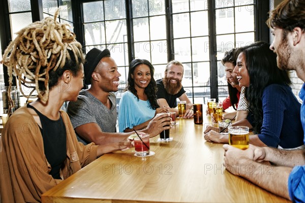 Smiling friends drinking at table in bar