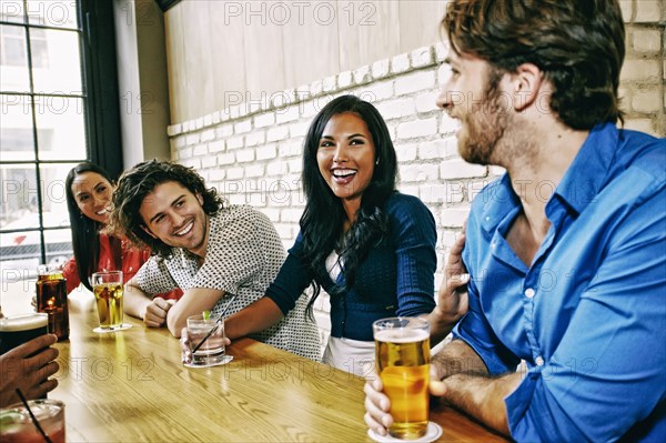 Smiling friends drinking at table in bar