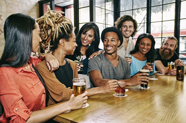 Smiling friends drinking at table in bar