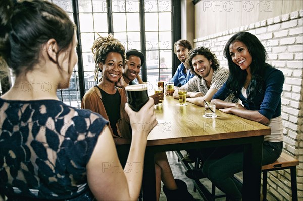Waitress serving smiling friends at table in bar