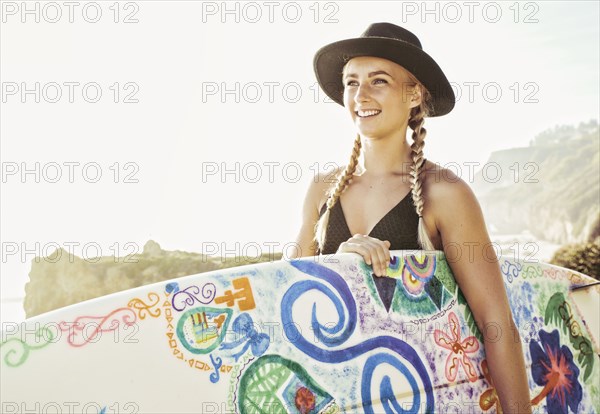 Caucasian woman carrying surfboard at beach