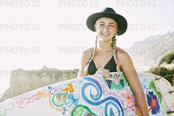 Caucasian woman carrying surfboard at beach