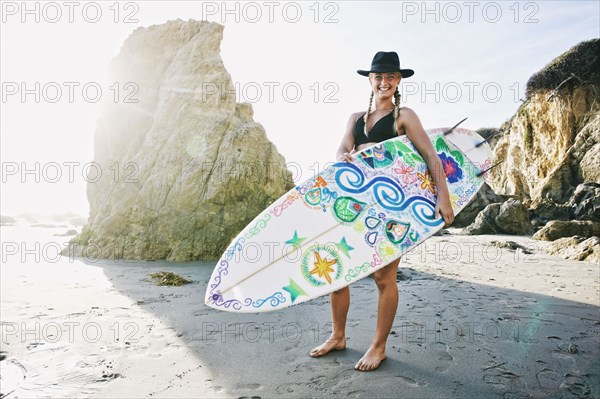 Caucasian woman carrying surfboard at beach