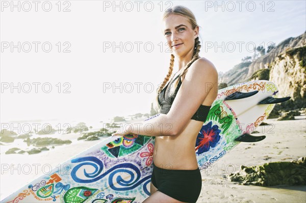 Caucasian woman carrying surfboard at beach