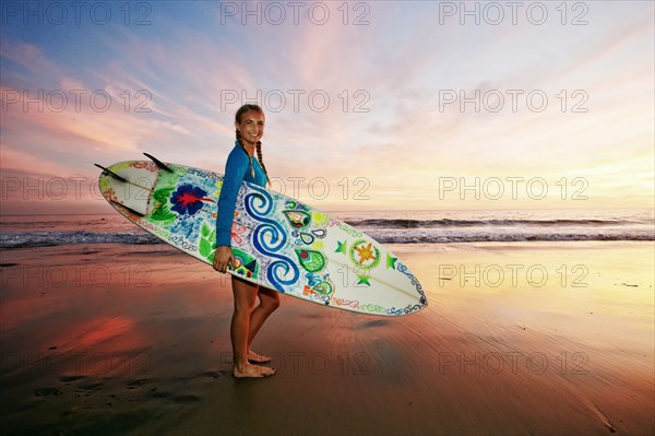 Caucasian woman carrying surfboard at beach