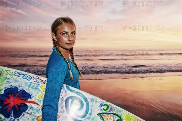 Caucasian woman carrying surfboard at beach