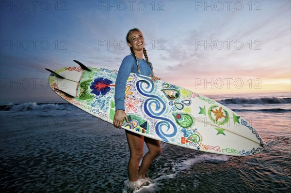 Caucasian woman carrying surfboard at beach