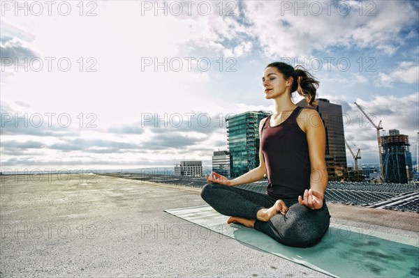 Caucasian woman meditating on urban rooftop