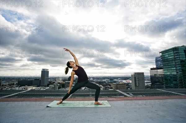 Caucasian woman stretching on urban rooftop