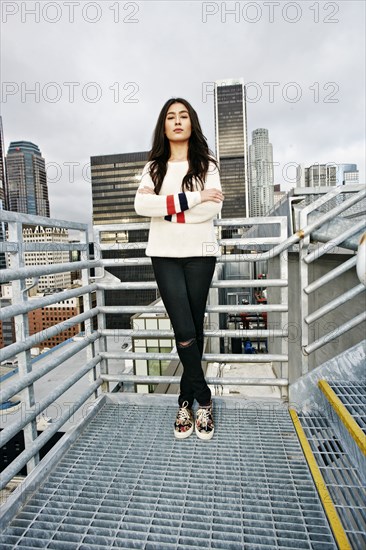 Serious Hispanic woman posing on urban metal staircase