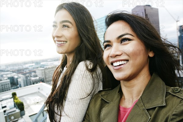 Women smiling in wind on urban rooftop