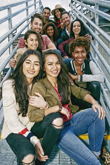 Stylish friends posing on urban metal staircase