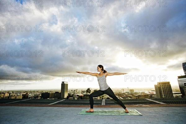 Caucasian woman stretching on urban rooftop