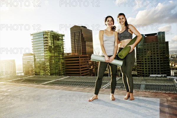 Caucasian women holding exercise mats on urban rooftop