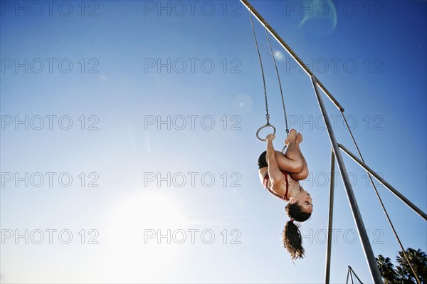 Caucasian woman using gymnastic rings at beach