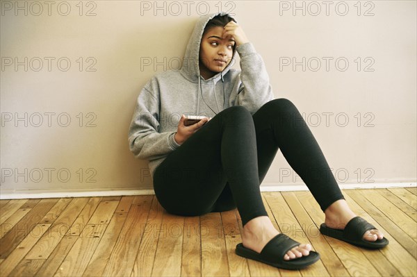 Mixed Race woman sitting on floor listening to cell phone