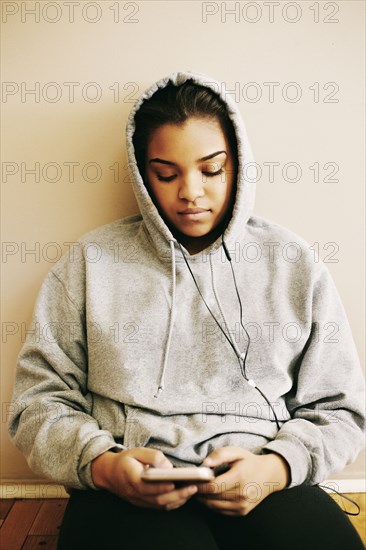 Mixed Race woman sitting on floor listening to cell phone