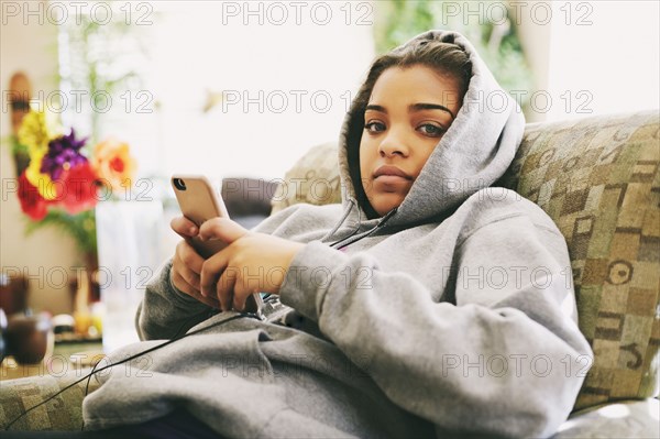 Mixed Race woman sitting on chair listening to cell phone