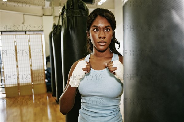 Black woman staring at heavy bag in gymnasium