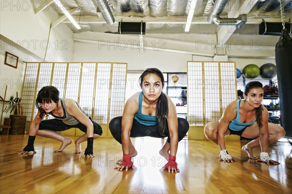 Women crouching on floor of gymnasium