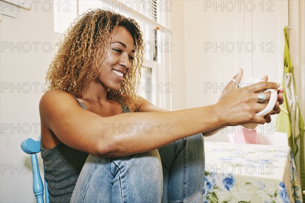 Smiling Mixed Race woman drinking coffee