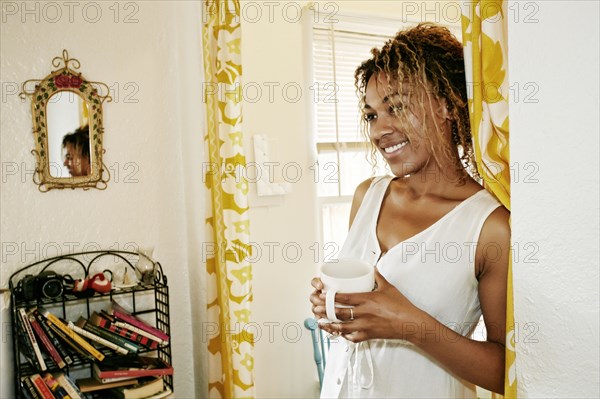 Smiling Mixed Race woman drinking coffee
