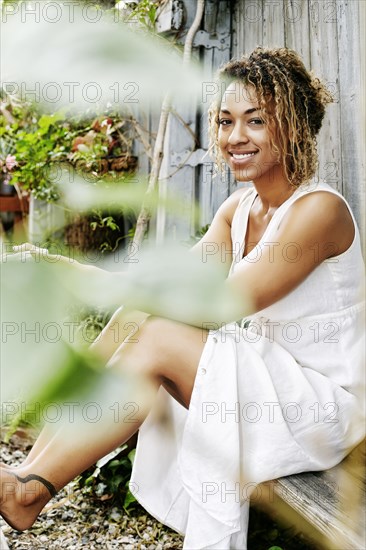 Smiling Mixed Race woman drinking coffee in garden