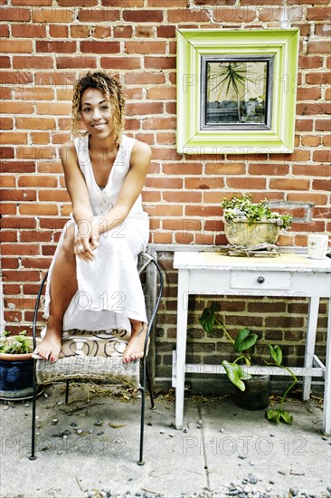 Smiling Mixed Race sitting on top of chair in garden