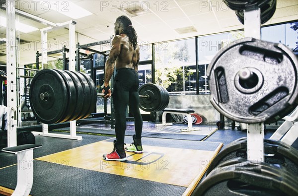 Black man lifting barbell in gymnasium