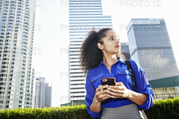 Hispanic businesswoman texting on cell phone outdoors