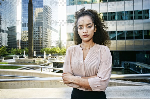 Serious Hispanic businesswoman posing outdoors